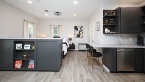 A modern kitchen with grey cabinetry, a built-in dishwasher, and a dining area with black chairs.
