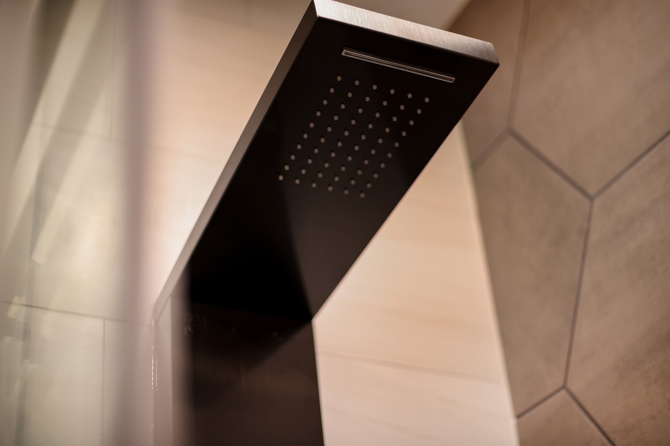 A modern shower with a sleek, black design and a unique, geometric pattern on the wall.