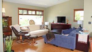 Una sala de estar con un sillón de cuero, un sofá azul, un televisor y una mesa de centro de madera.