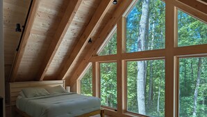 Un dormitorio con techo de madera, ventanas amplias y una cama.
