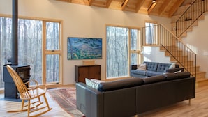 Un amplio salón con un sofá grande, un sillón mecedora, una chimenea y una escalera.