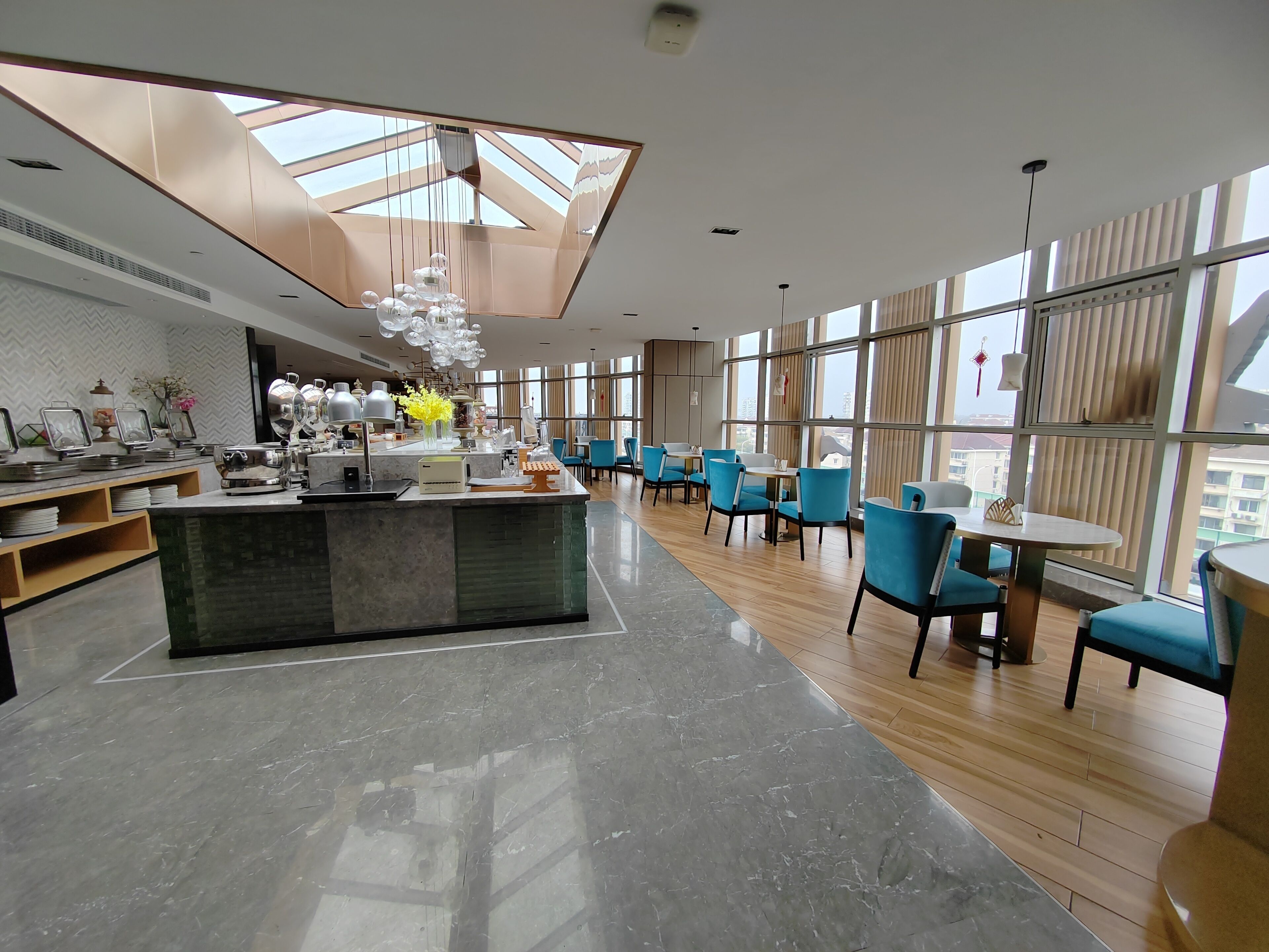Un comedor moderno con una isla central, sillas azules y ventanas amplias que ofrecen vistas de la ciudad.
