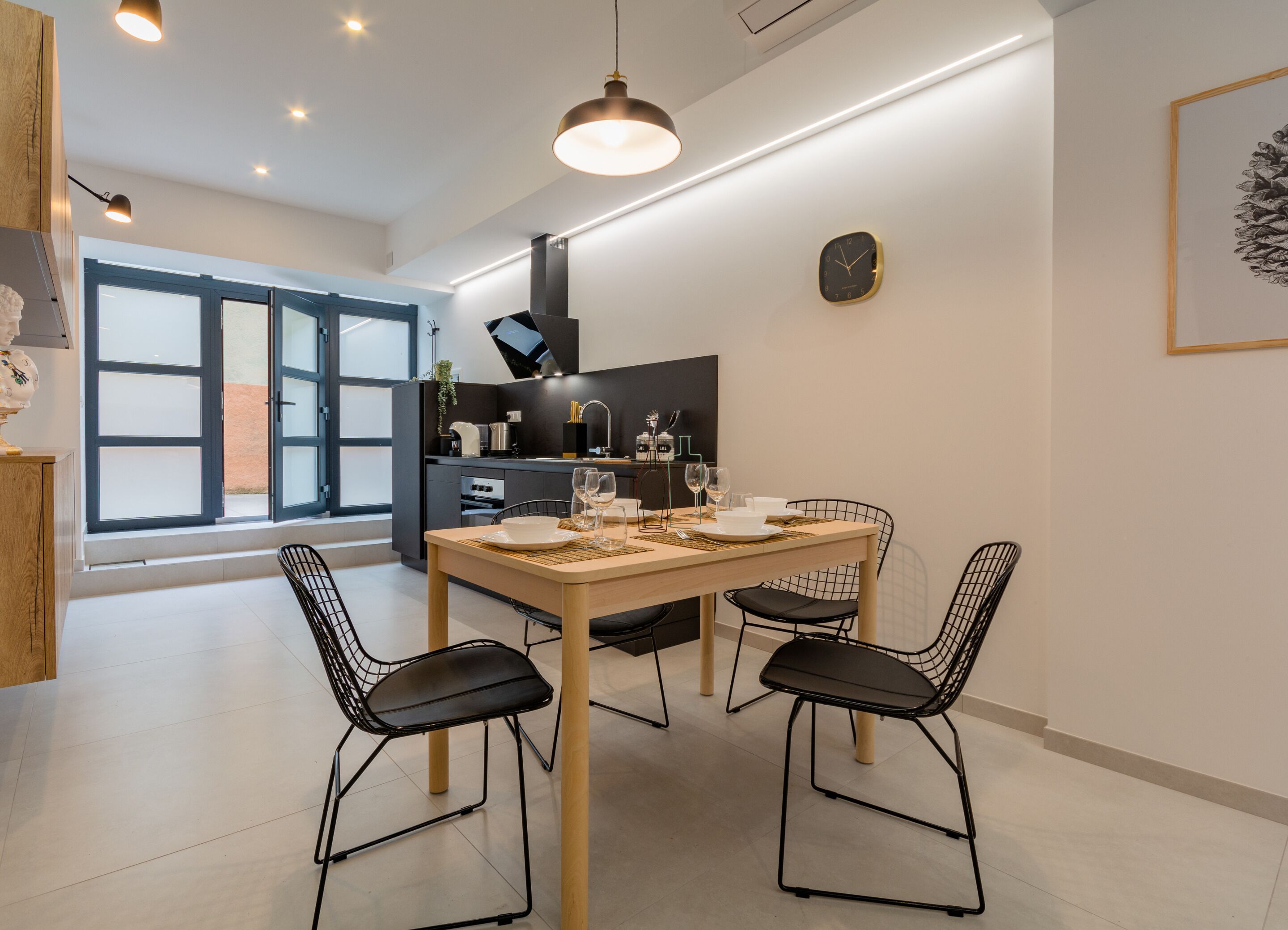 Une cuisine moderne avec un coin repas, comprenant une table en bois, des chaises noires et une grande fenêtre offrant une belle vue.