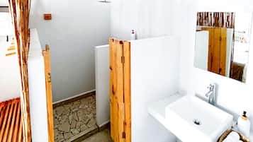 Un baño con lavamanos blanco, espejo y zona de ducha.