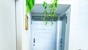 A narrow hallway with a tiled floor, a door at the end, and a hanging plant. - Corazon de Teco (Tecolutla)