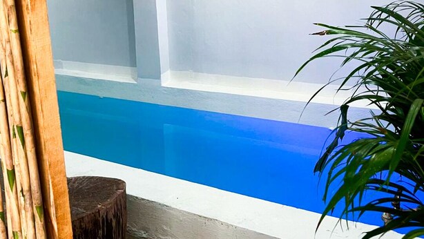 A swimming pool with a blue interior, surrounded by a white wall and a wooden deck. - Corazon de Teco (Tecolutla)