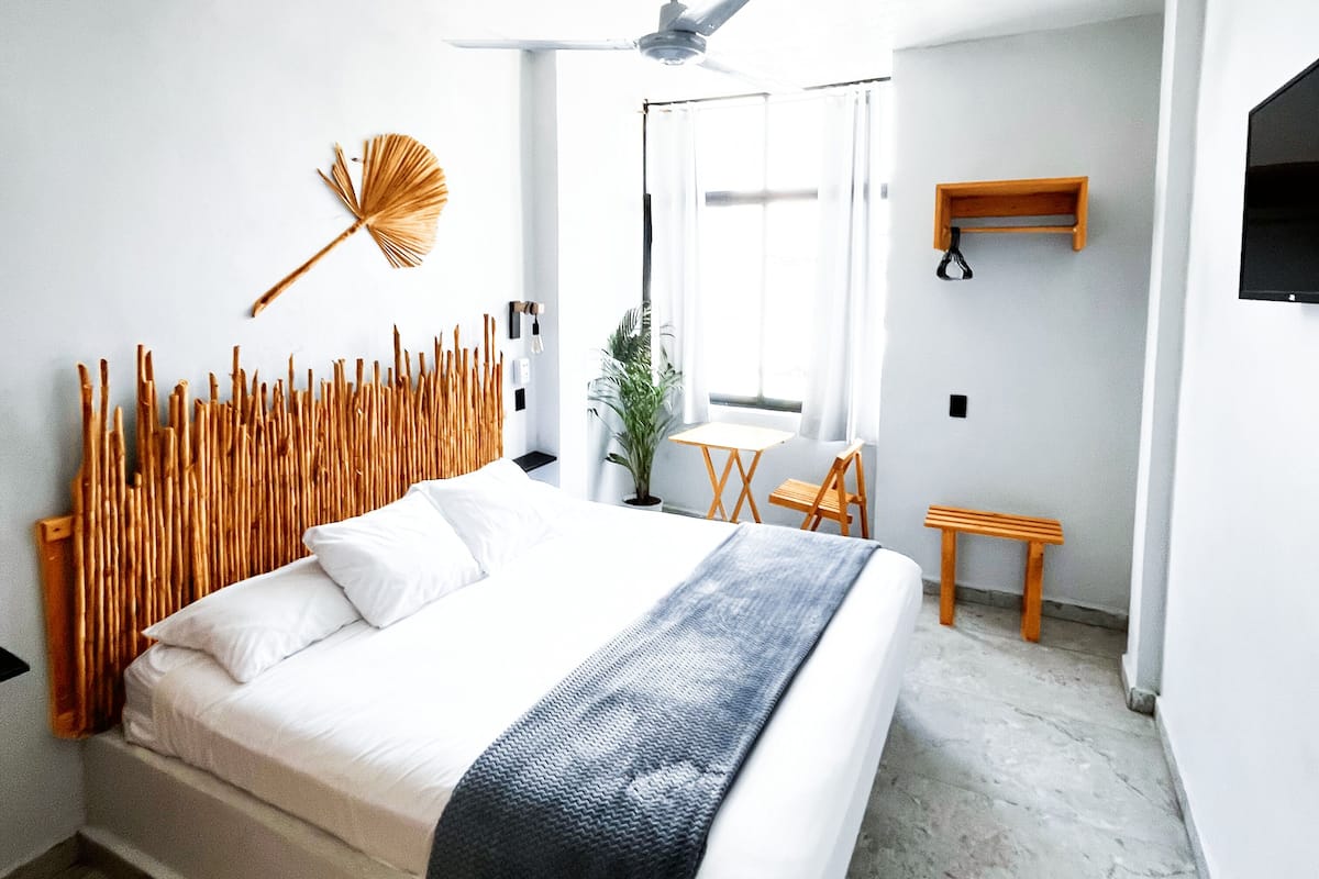 A modern bedroom with a large bed, a ceiling fan, and a window with curtains.