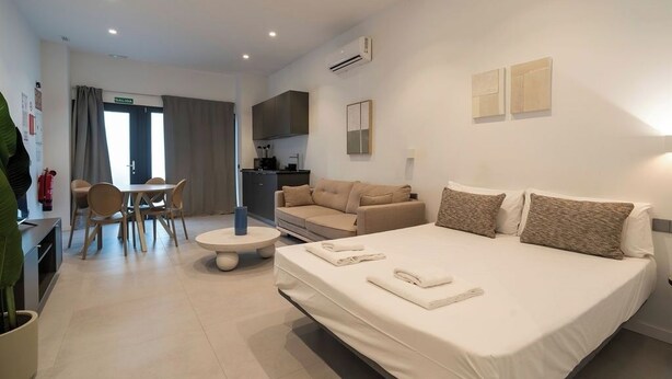 Een moderne hotelkamer met een groot bed, een bank, een eettafel en een kitchenette.