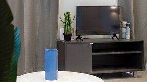 Ett modernt vardagsrum med ett runt, vitt soffbord, en platt-tv på ett svart stativ och en krukväxt.