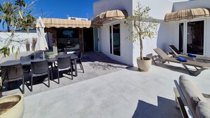 Une terrasse sur le toit comprenant un espace repas, des chaises longues et un arbre en pot.