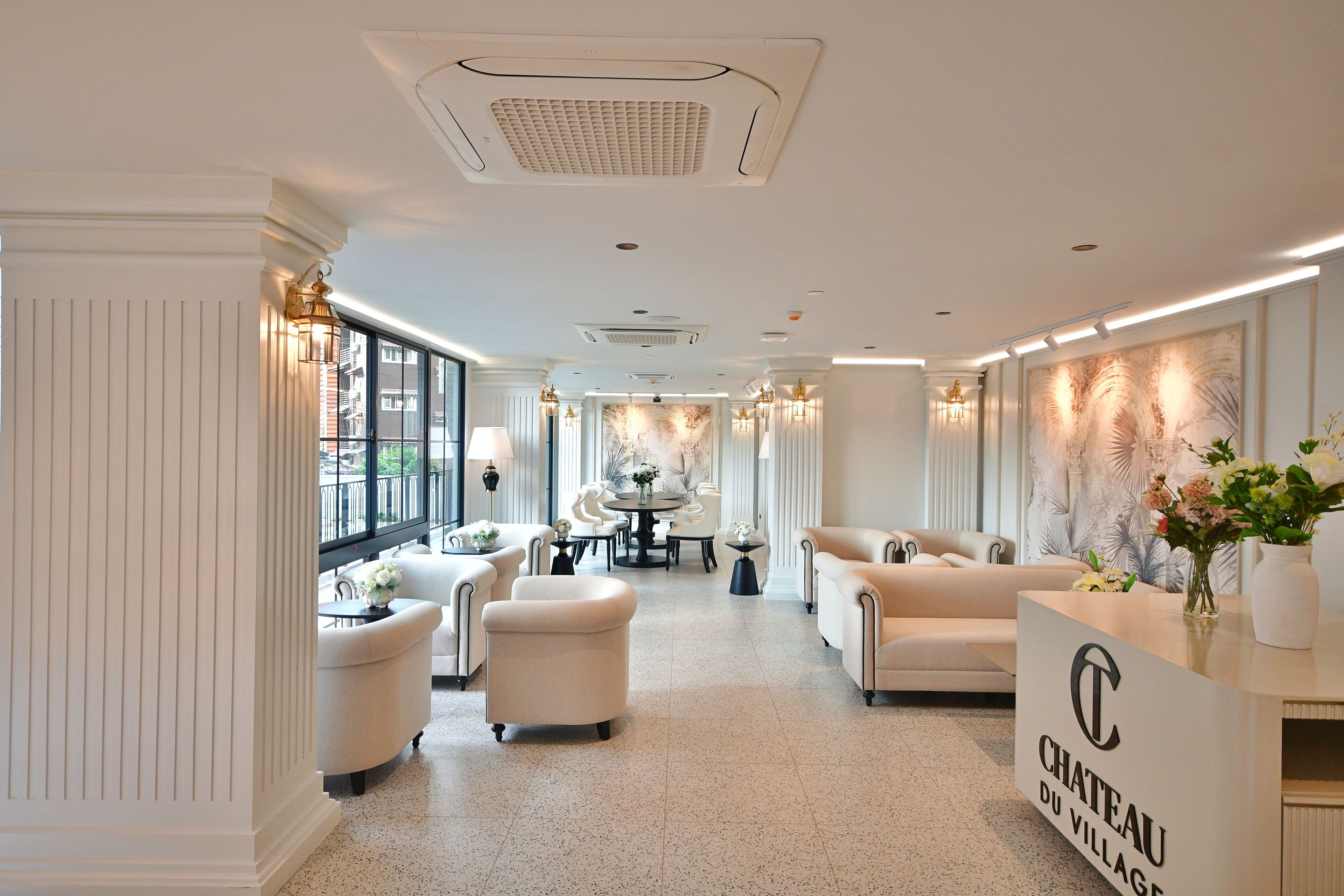 A spacious hotel lobby with a high ceiling, elegant furniture, and a reception desk.