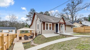 A single-story house with a front porch, a wooden deck, and a fenced backyard. - ATL Oasis: Home Away From Home (Atlanta)