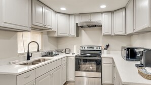 A kitchen with white cabinets, a stainless steel oven, a microwave, and a sink. - ATL Oasis: Home Away From Home (Atlanta)