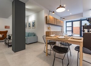 A modern kitchen with a dining area, featuring a wooden table, black wire chairs, and pendant lighting. - Battle Kitchen Loft (Milan)