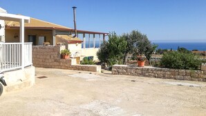 Une propriété située en bord de mer, dotée d’un balcon, de plantes en pot et offrant une vue sur la mer.