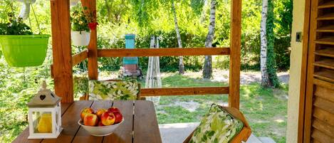 A wooden deck with a table, chairs, and a bowl of apples.