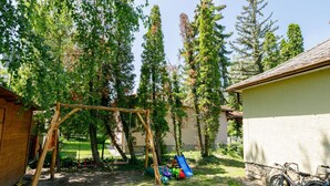 A backyard with a wooden swing set, a slide, and a bicycle.