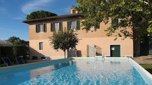 A swimming pool with clear water, surrounded by a building with green shutters, a tree, and a fence. - Beautiful private villa for 33 people with private pool, WIFI, TV, patio and pets allowed (San Miniato)