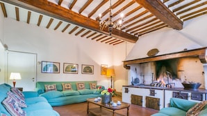 A cozy living room with a green sofa set, a coffee table, and a fireplace. - Beautiful private villa for 33 people with private pool, WIFI, TV, patio and pets allowed (San Miniato)