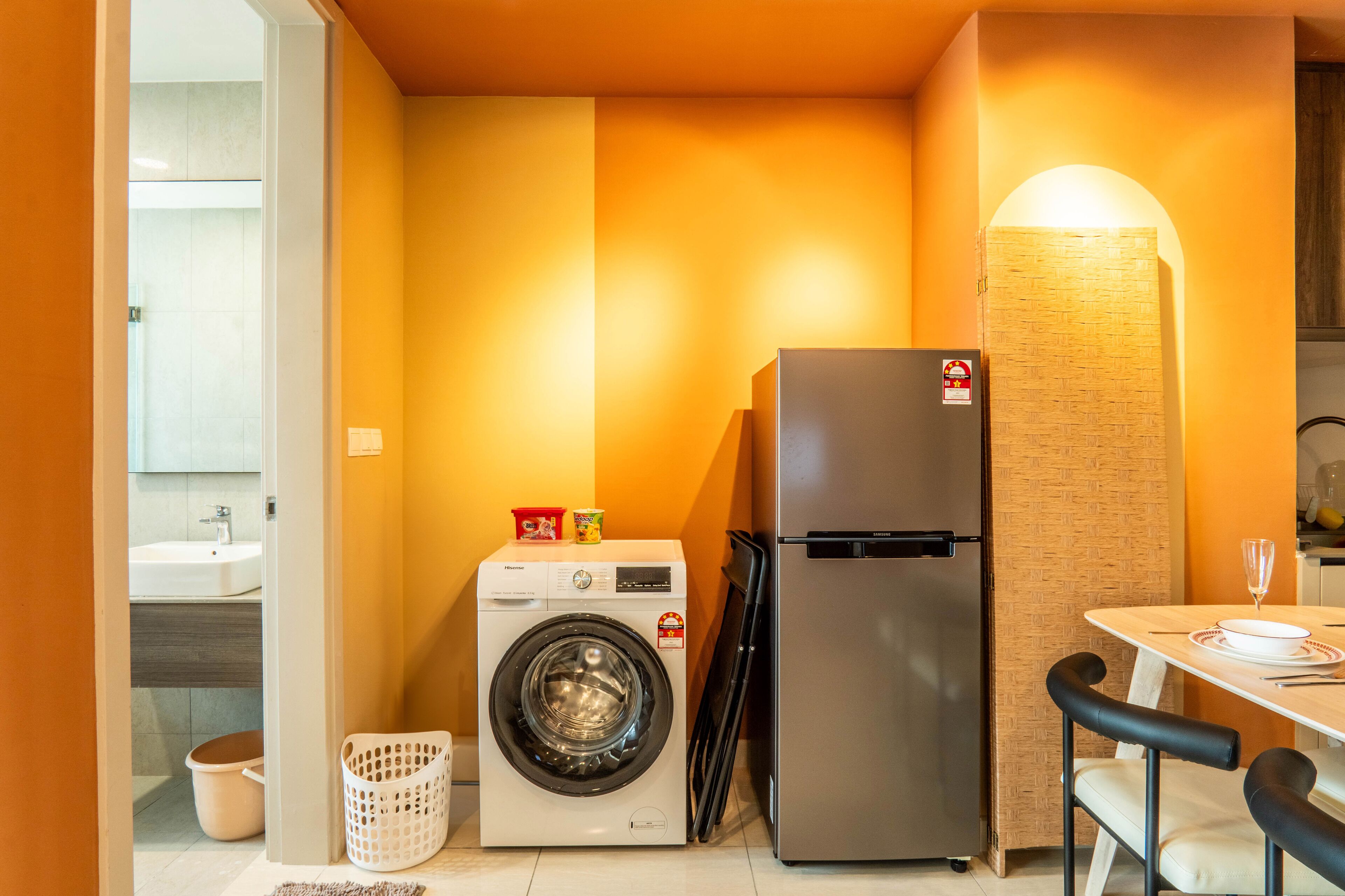 Une cuisine compacte équipée d’un lave-linge, d’un réfrigérateur et d’une table avec des chaises.