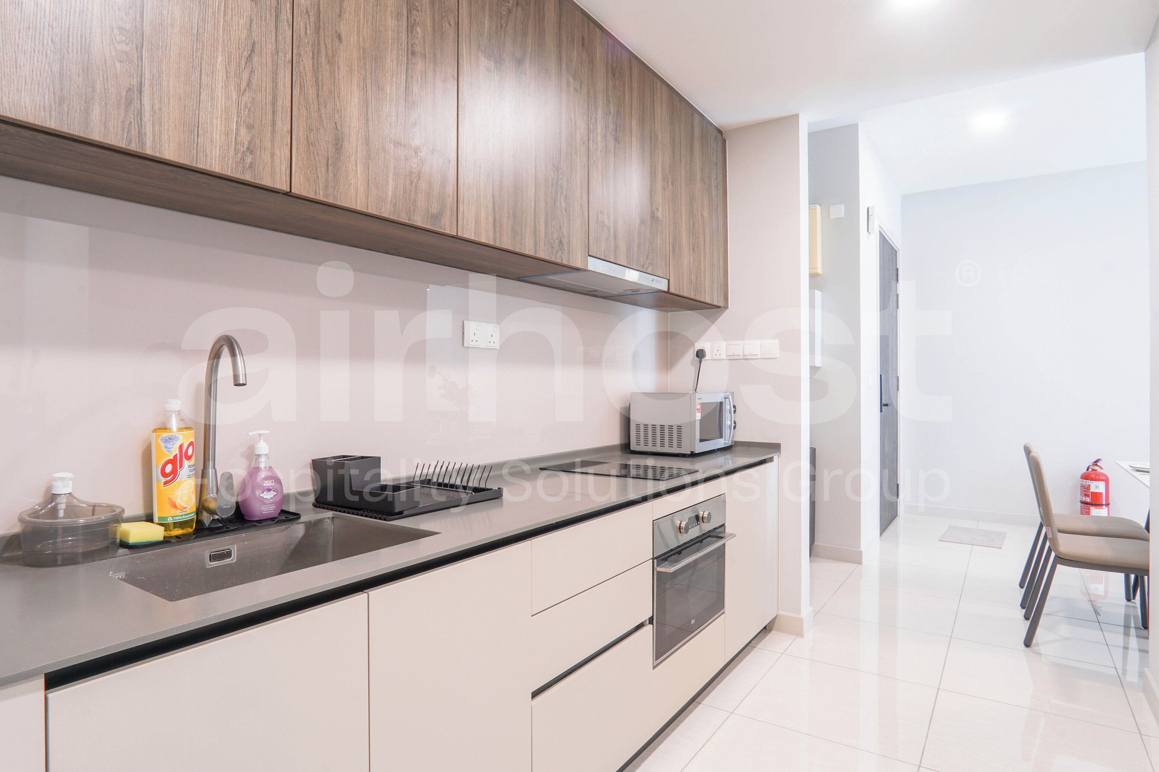 A modern kitchen with wooden cabinets, a built-in oven, and a microwave.