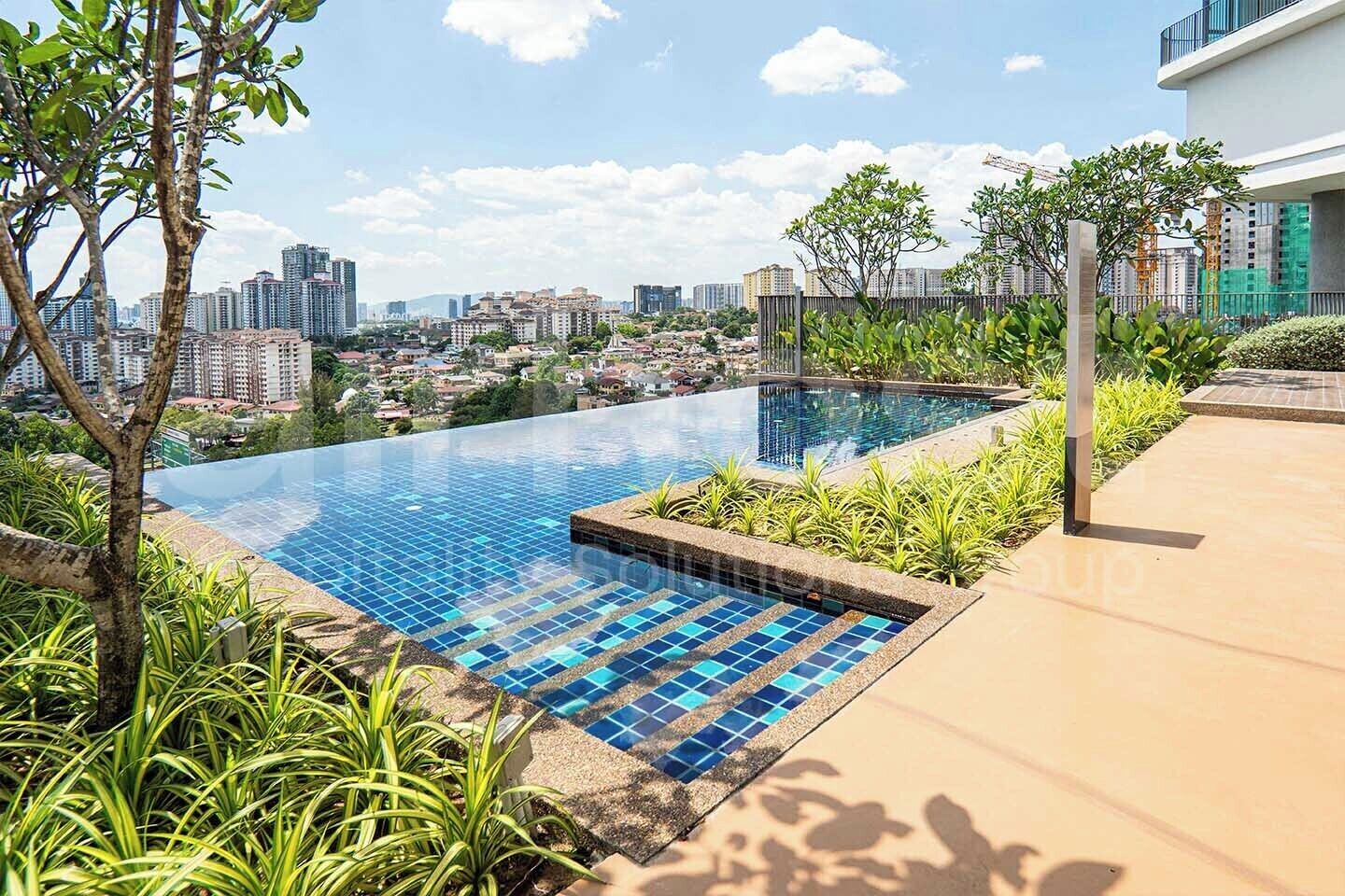 An infinity pool with a city view, surrounded by greenery and a modern building.