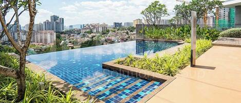 An infinity pool with a city view, surrounded by greenery and a modern building.