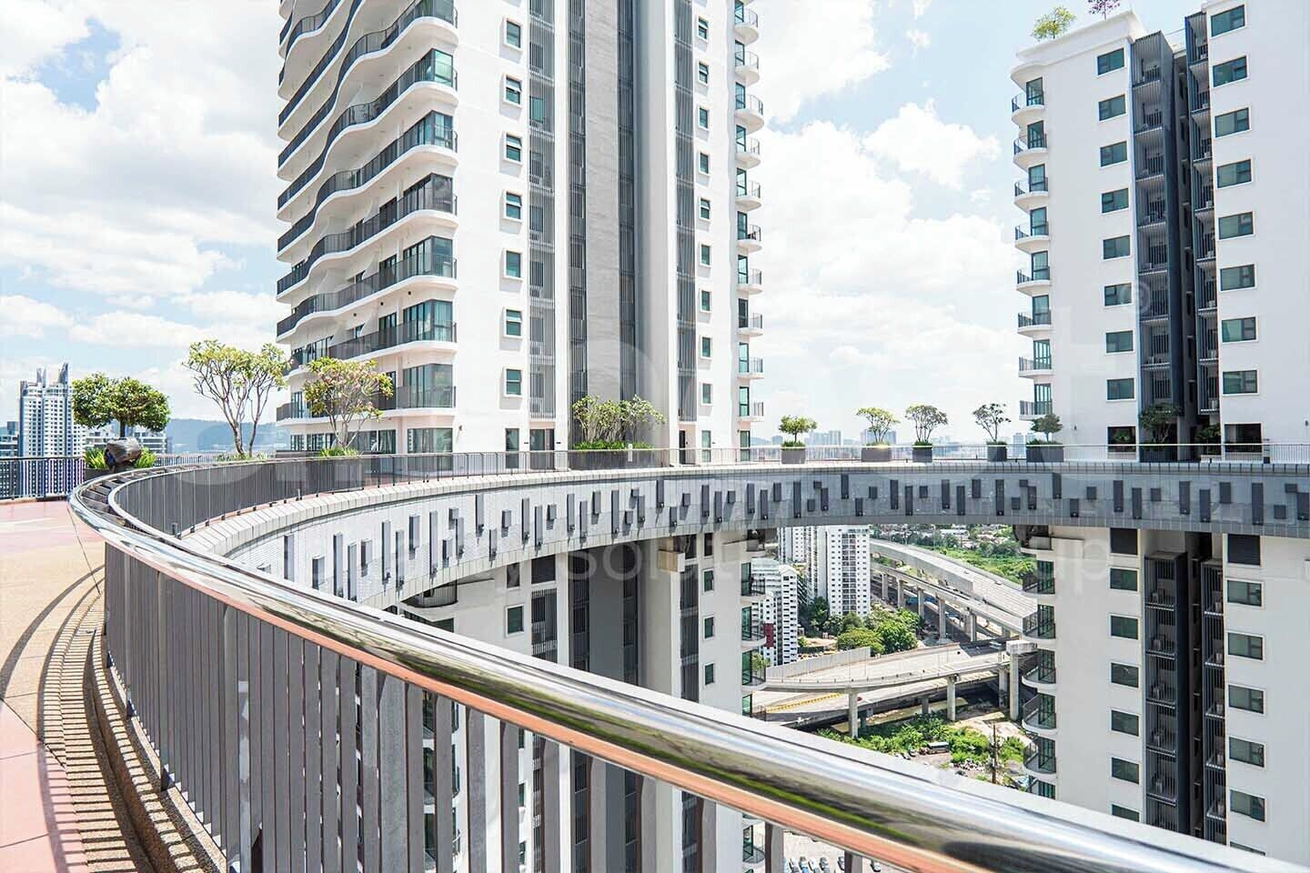 A modern high-rise building with a curved pedestrian bridge connecting to another building.