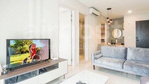 Een moderne woonkamer met een flatscreen televisie, een grijze bank en een salontafel.
