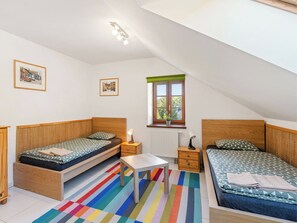 Ein kleiner, hell eingerichteter Raum mit zwei Betten, einem Tisch und einem Fenster.