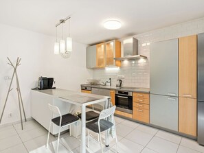 Een moderne keuken met een centraal eiland, roestvrijstalen apparatuur en lichtgekleurde kastjes.