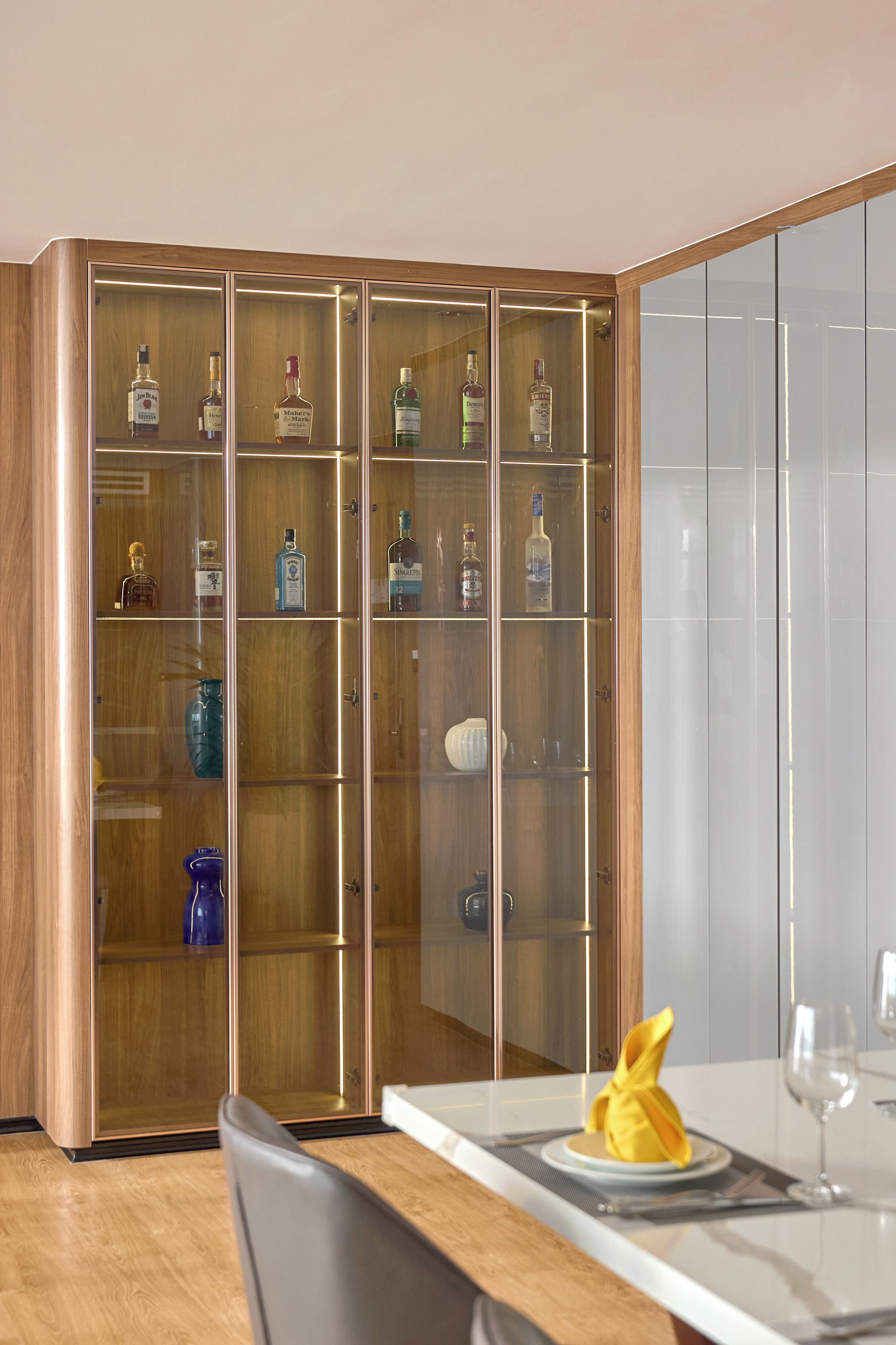 A modern dining area with a wooden cabinet containing various liquor bottles.