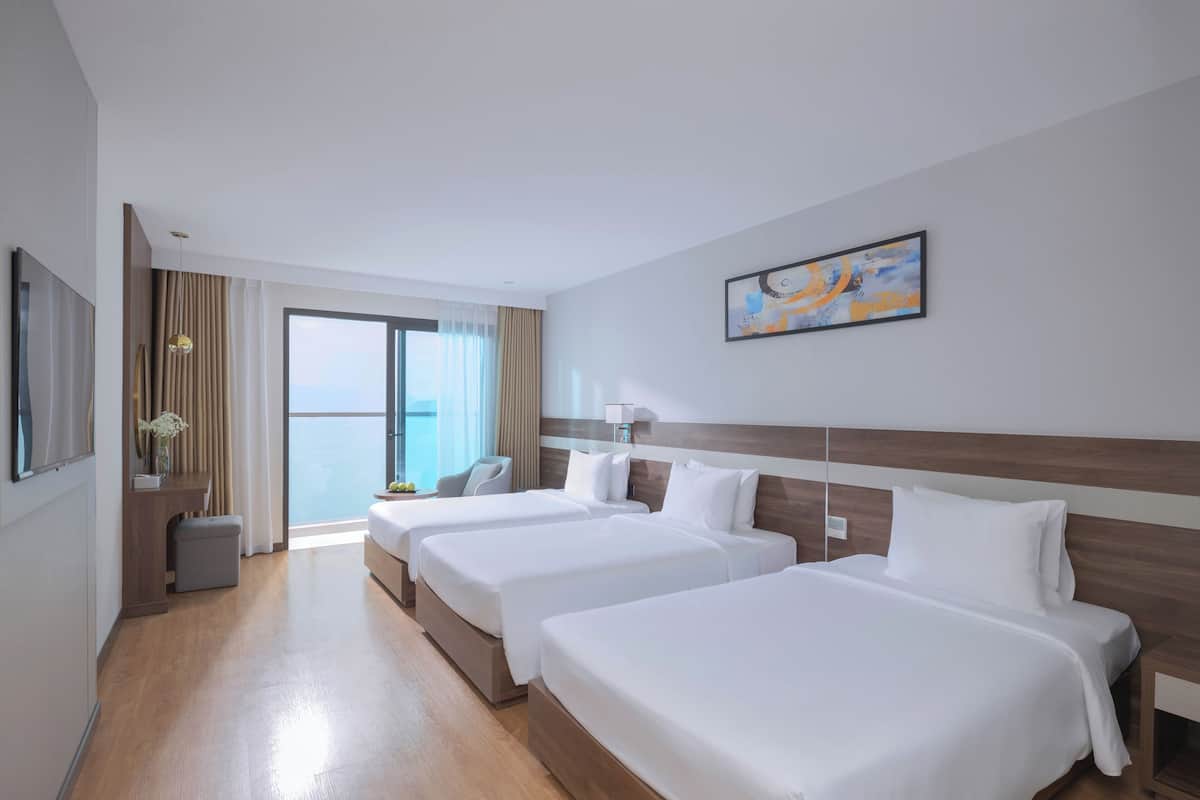 Een hotelkamer met twee bedden, een bureau, een stoel en een groot raam met uitzicht.