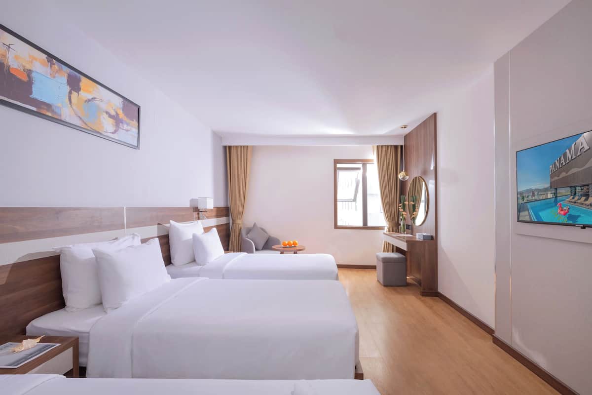 Een hotelkamer met twee bedden, een televisie, een bureau en een raam met gordijnen.