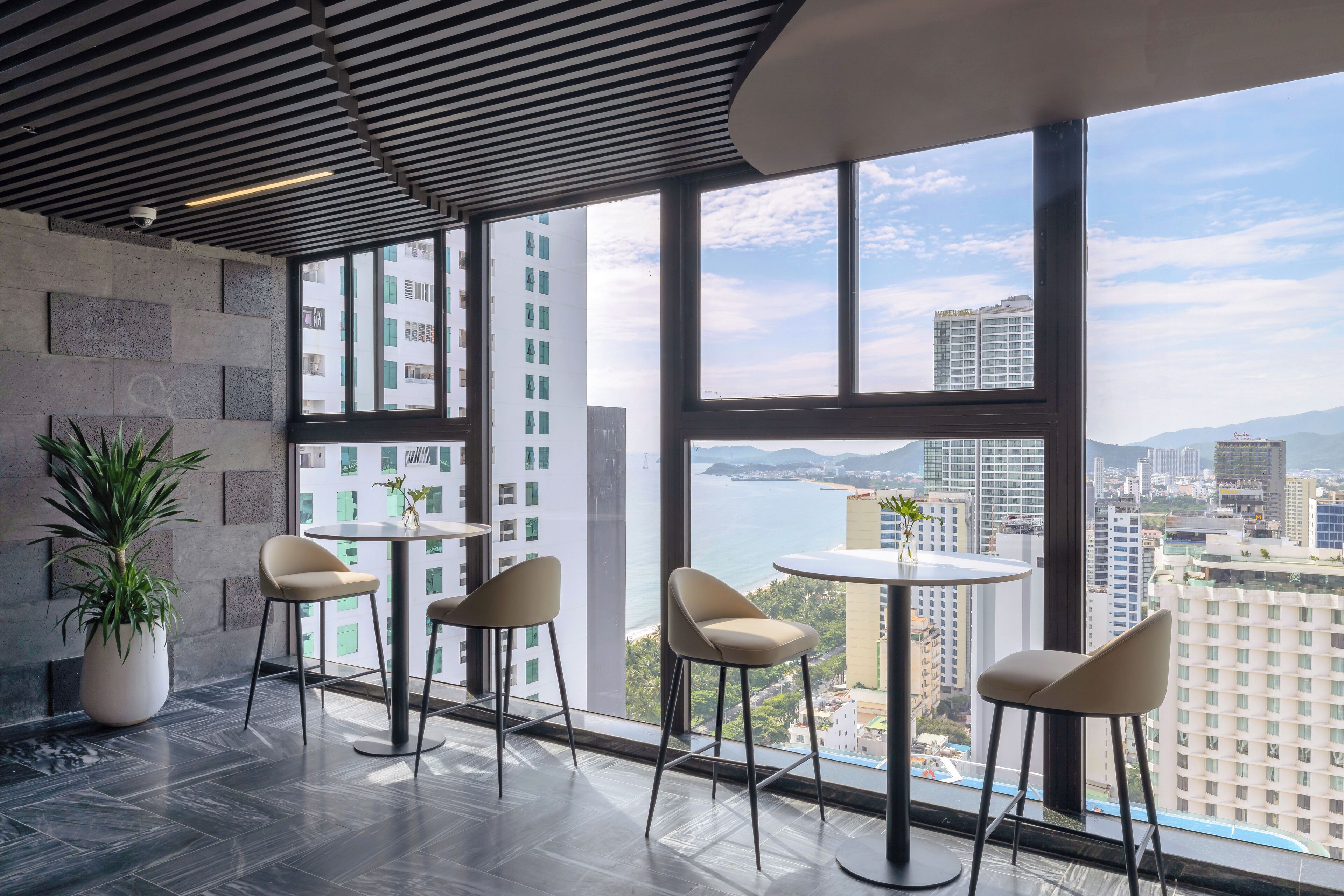 Un interior moderno con ventanas amplias, una planta en maceta y vistas a la ciudad.