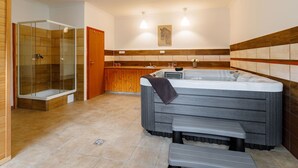 A modern bathroom with a glass-enclosed shower, a large bathtub, and a bench.