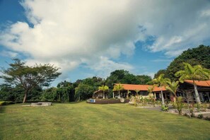 A hotel with a red roof, surrounded by lush greenery and a clear sky.