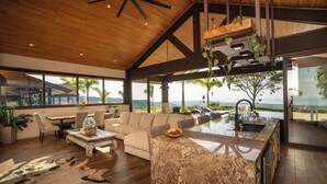 A spacious living area with a large sofa, a dining table, and a kitchen island with a sink.