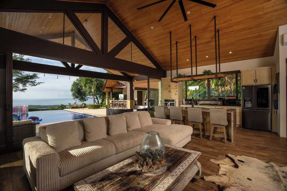A modern living room with a sofa, a coffee table, and a view of the ocean.