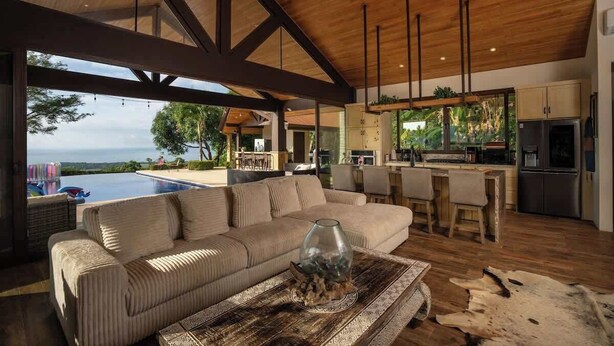 A modern living room with a sofa, a coffee table, and a view of the ocean.