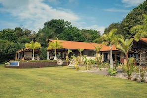 Un resort con dos edificios, una piscina y abundante vegetación.