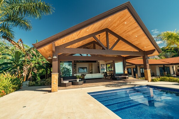 Relax by the pool surrounded by lush tropical plants and palm trees.