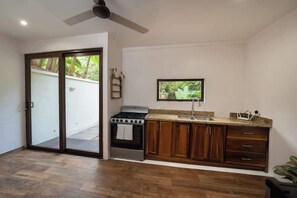 A kitchen with a gas stove, wooden cabinets, a window, and a sliding glass door leading to an outdoor area.