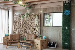 A room with a wooden wall decoration, two leather sofas, a side table with a blue candle, and a pet bed. - Casa Serendida, with Panoramic Views (Playa Hermosa)