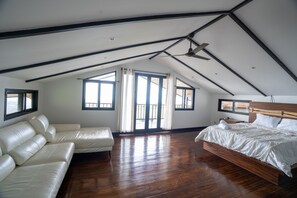 Relax in this airy room with a large bed and comfortable sofa, surrounded by natural light and exposed beams.