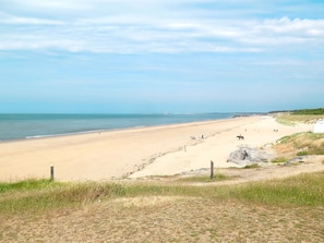 Enjoy a serene beach experience with gentle waves and a picturesque lighthouse in the distance.