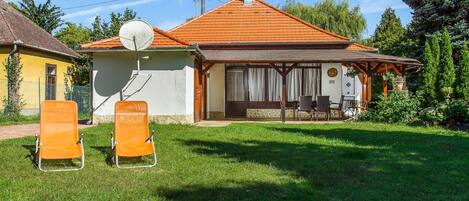 Een huis met een pannendak, een schotelantenne en een terras met stoelen.
