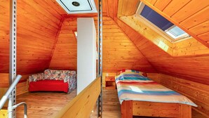 A small, wooden attic bedroom with a sloped ceiling, a skylight, a bed, a bench, and a small table. - Wonderful private villa for 4 people with WIFI, A/C, TV and terrace (Keszthely)