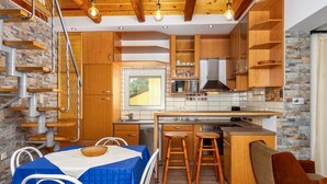 A modern kitchen with wooden cabinets, a built-in stove, and a dining area with a table and chairs. - Wonderful private villa for 4 people with WIFI, A/C, TV and terrace (Keszthely)