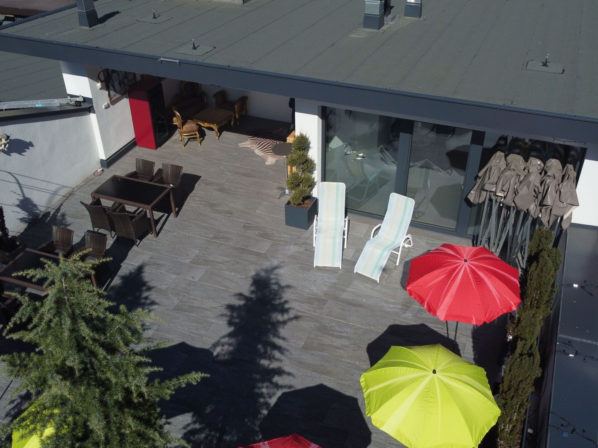 Eine Außenpatio-Terrasse mit Sitzgelegenheiten, Sonnenschirmen und einem Blumentopf.